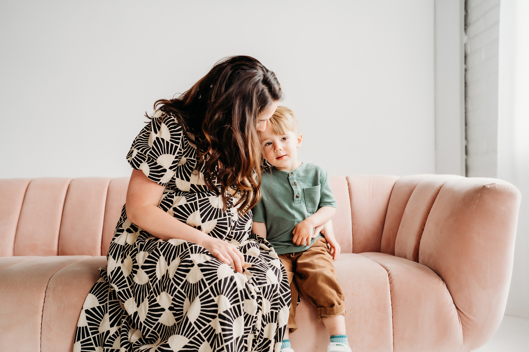 Denver Family Photographer captures mother hugging son on pink couch during in-home family photos