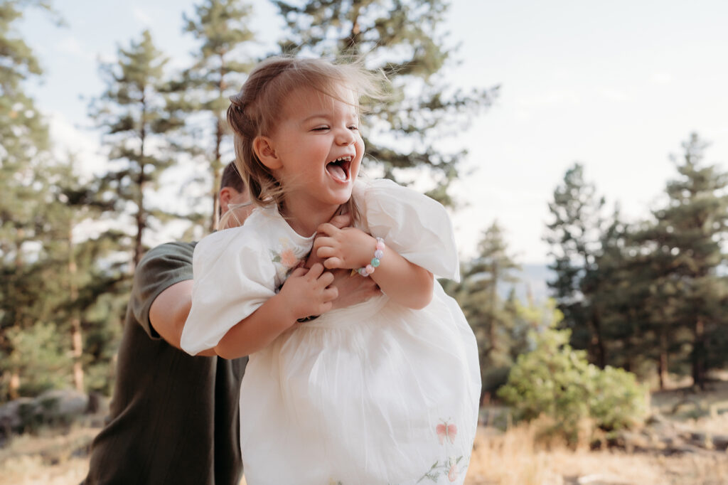 Denver Family Photographer captures father lifting baby in air and making her laugh