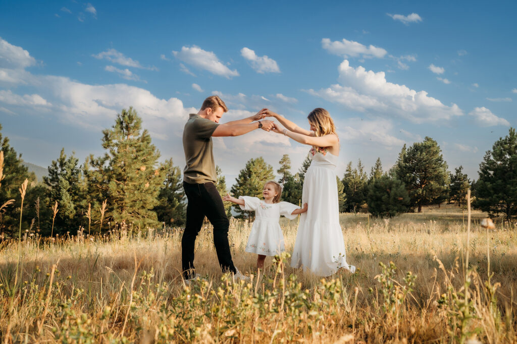 Denver Family Photographer captures mom and dad playing with daughter in field of flowers