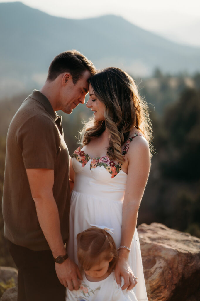 Denver Family Photographer captures mom and dad touching foreheads while holding daughters hand