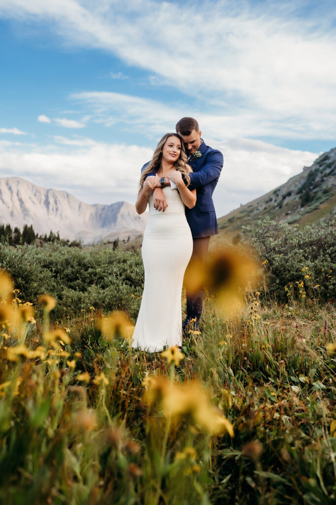 Colorado Elopement Photographer captures bride and groom hugging in field of wildflowers