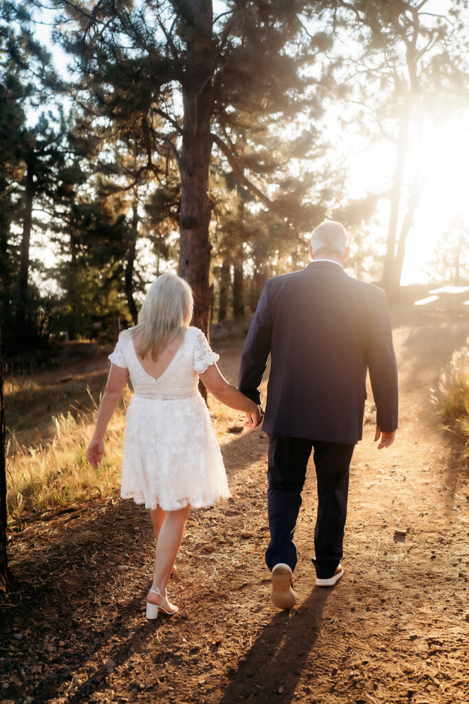 Colorado Elopement Photographer captures bride and groom walking hand in hand during golden sunset