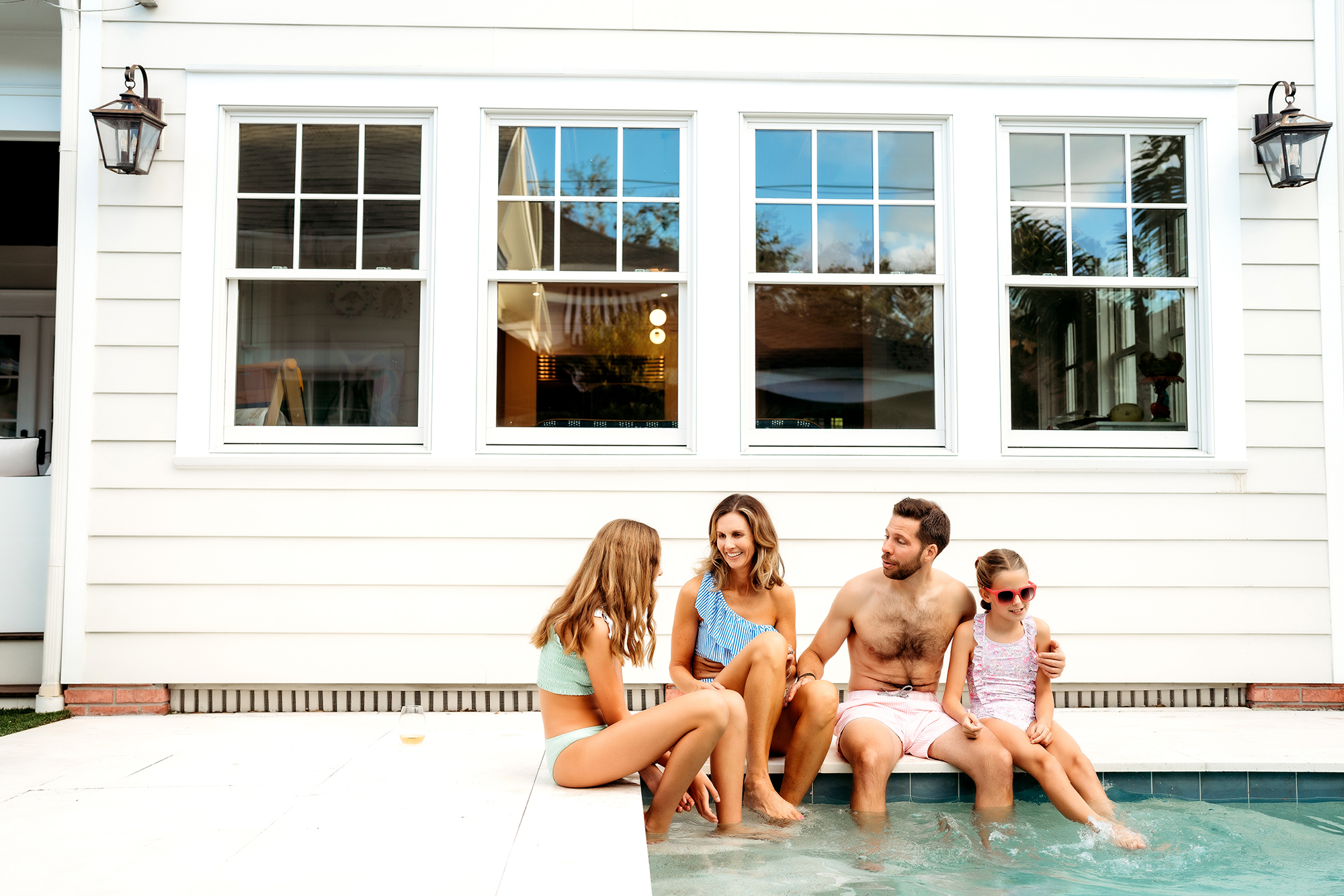 Denver Family Photographer captures young family sitting poolside during family swim party in Denver