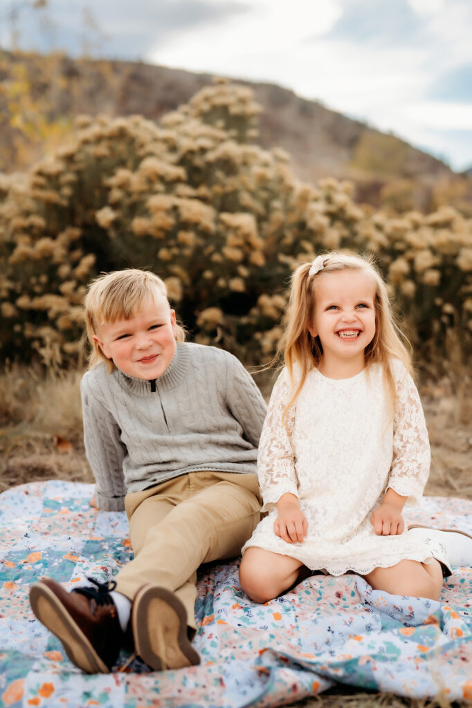 Denver Family Photographer captures young kids sitting on blanket smiling during outdoor family photos in Colorado