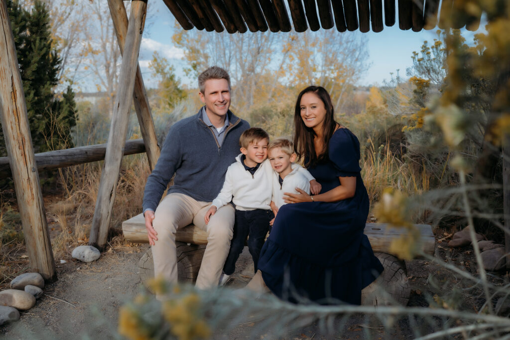 Denver Family Photographer captures family sitting on a bench together during fall outdoor photos