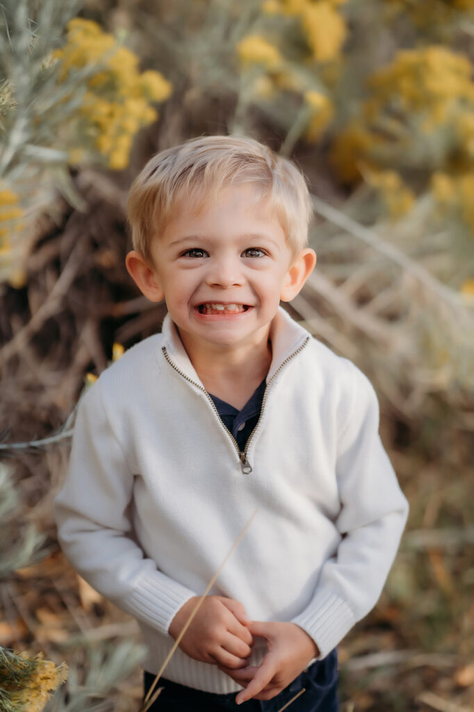 Denver Family Photographer capture young boy smiling at camera wearing white sweater