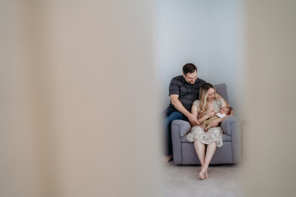 Denver Family Photographer captures young family sitting on chair  holding baby during lifestyle photography