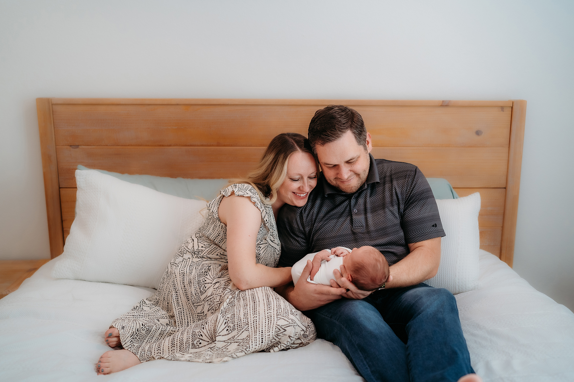 Denver Family Photographer captures young family sitting in bed together during lifestyle photos in home