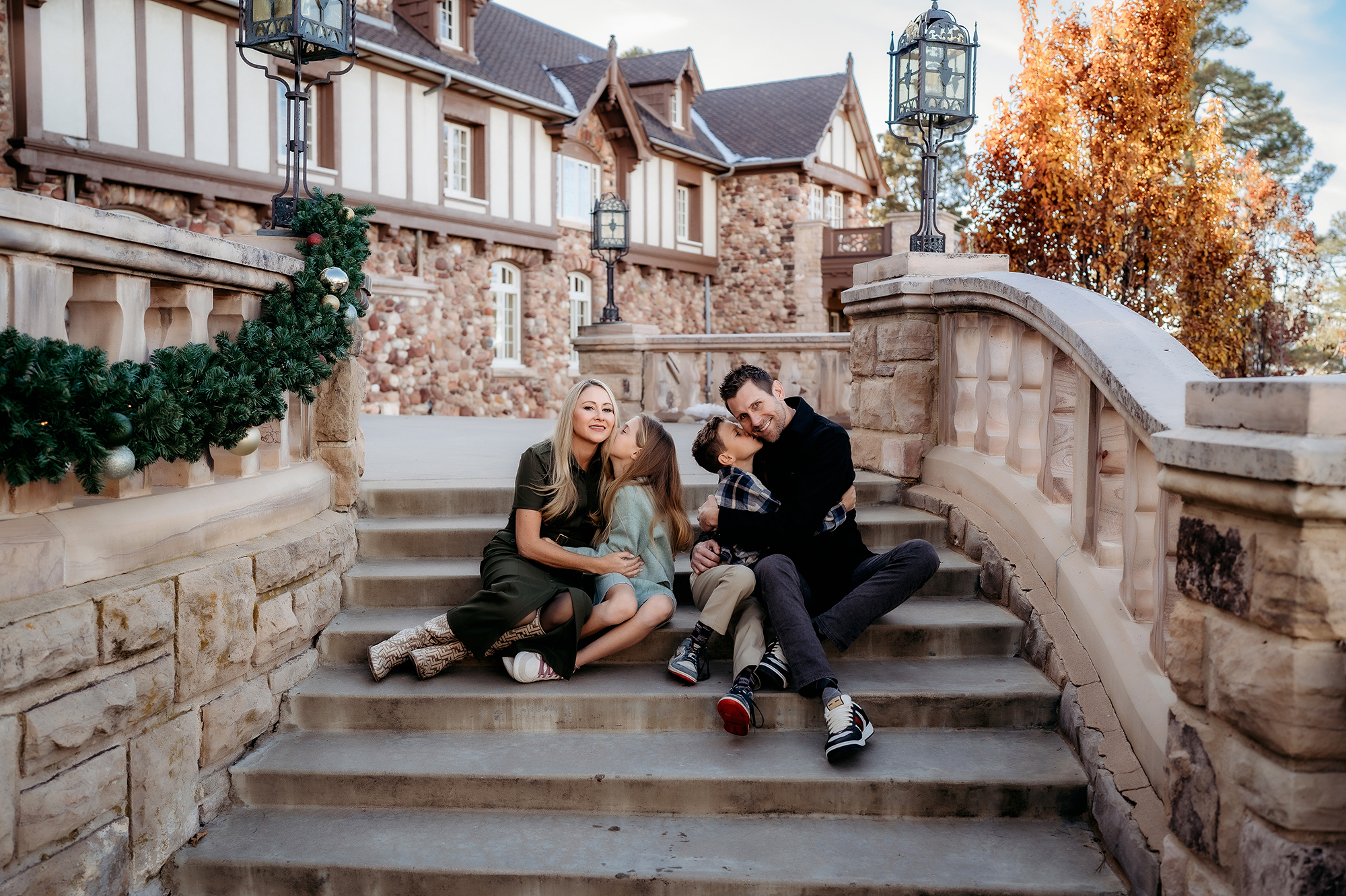 Family sitting together on stone steps, dressed in cozy coordinated outfits for family photos.
