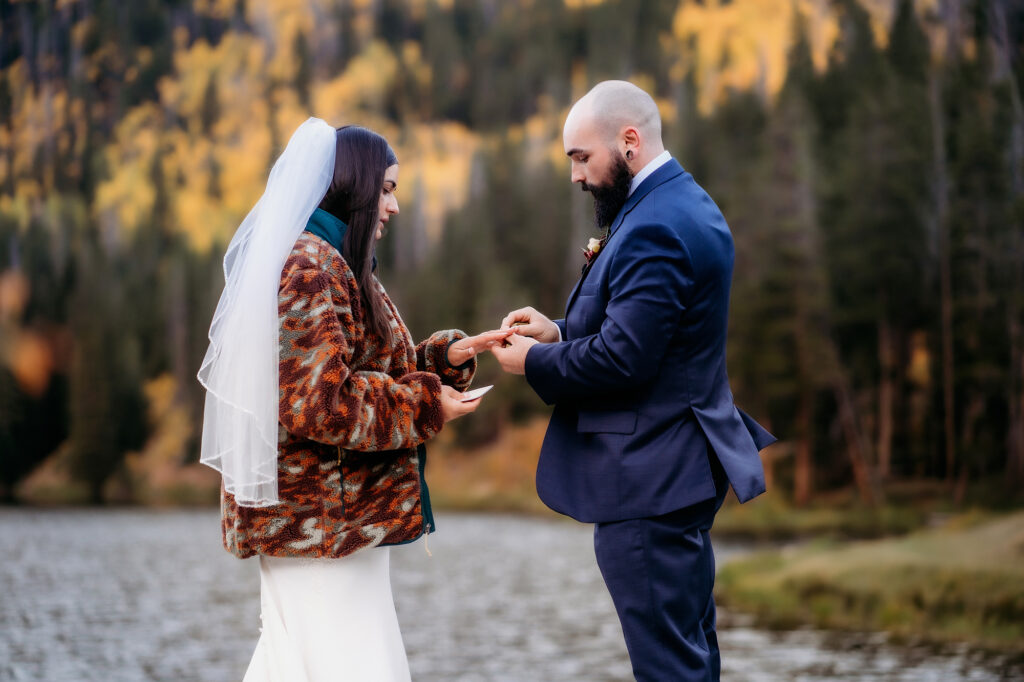 Colorado Elopement Photographer captures bride and groom holding hands while exchanging vows