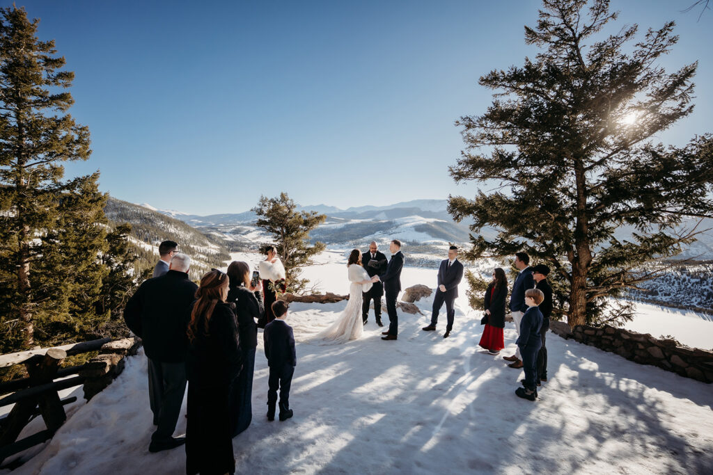 A couple exchanges vows on a snowy overlook surrounded by family, capturing the best day of your life with a sweeping Colorado mountain backdrop.