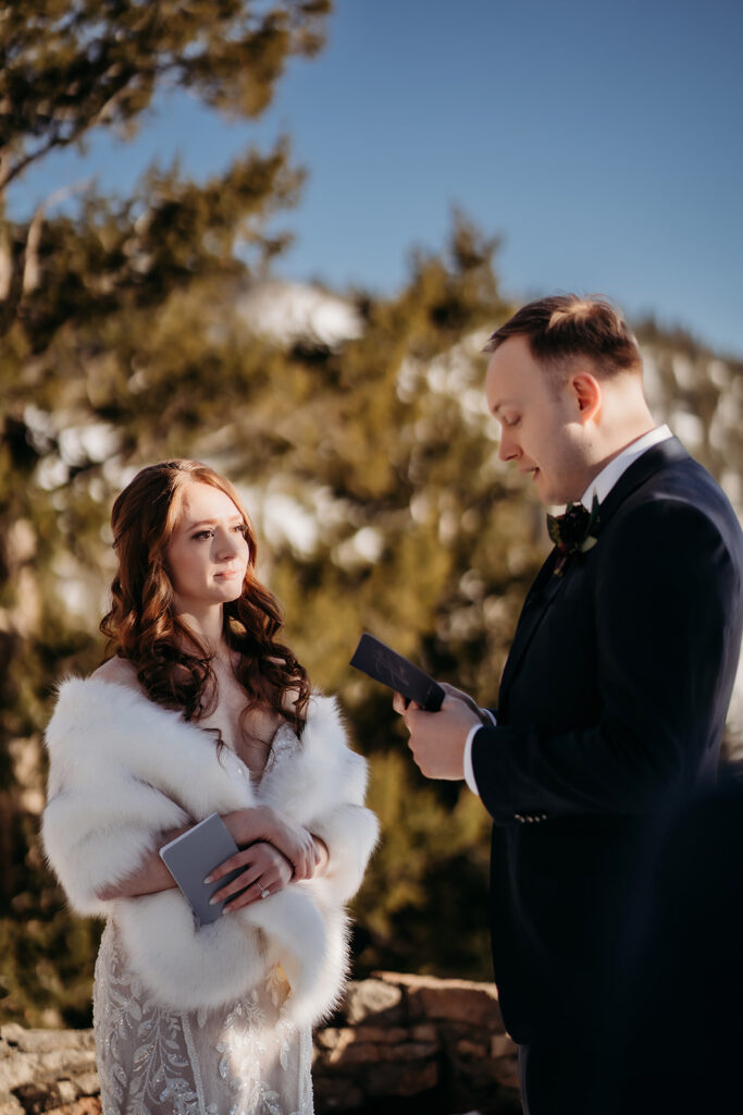 Bride listens intently as her partner reads vows, bathed in golden morning light—Colorado elopement photographer.
