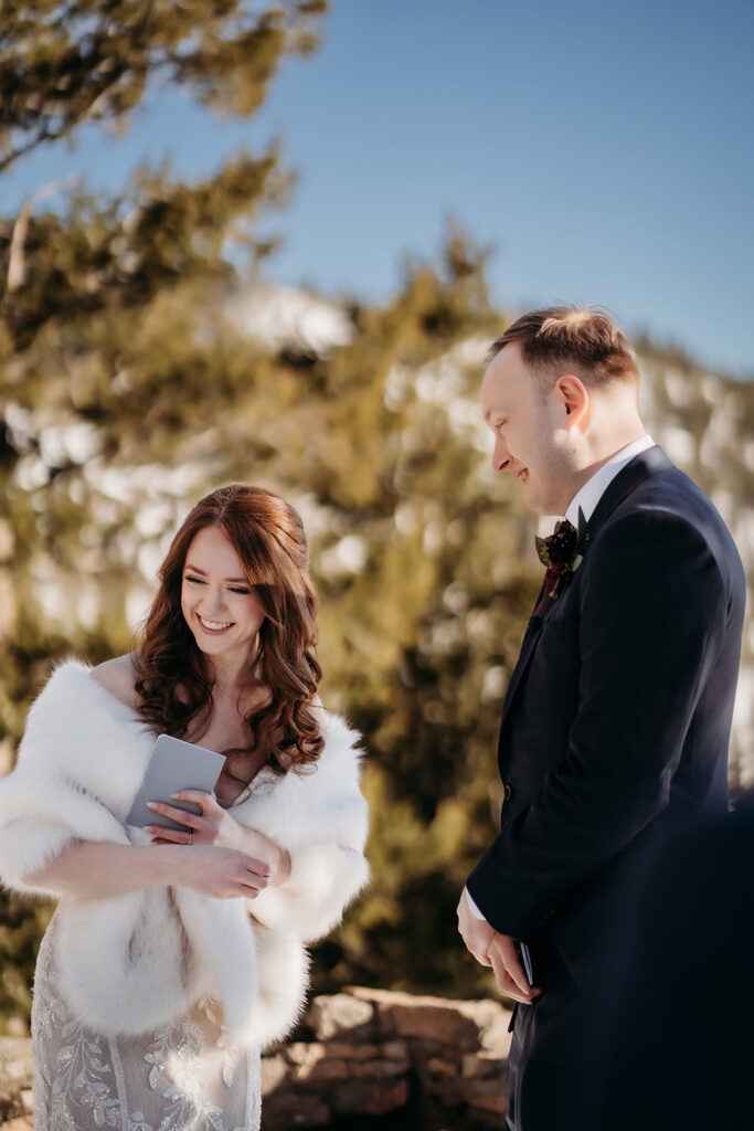 Couple shares a laugh mid-ceremony as they read personal vows, wrapped in fur and emotion.