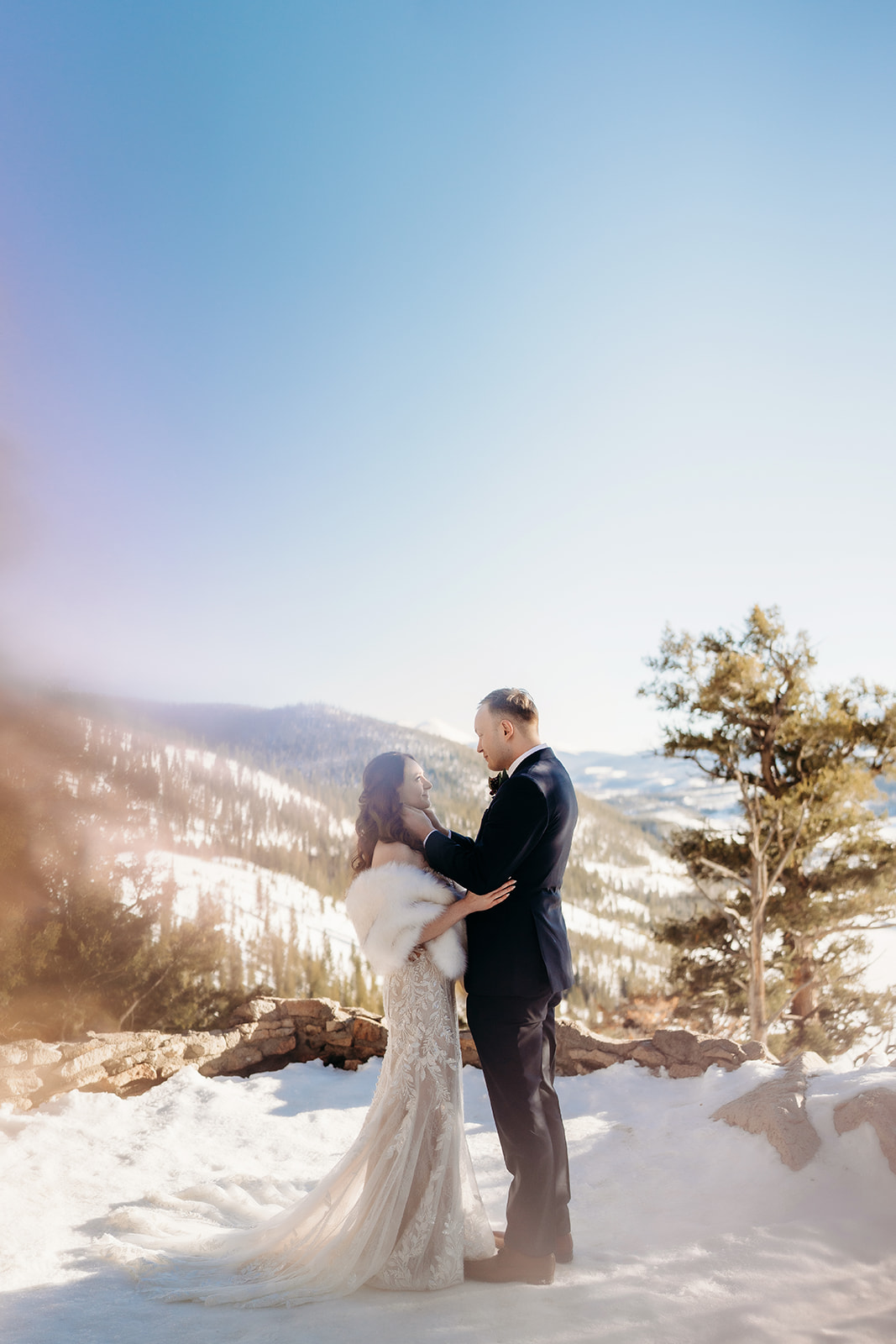 A gentle kiss shared by newlyweds with fresh snow and evergreen trees in the distance—Colorado elopement photographer.
