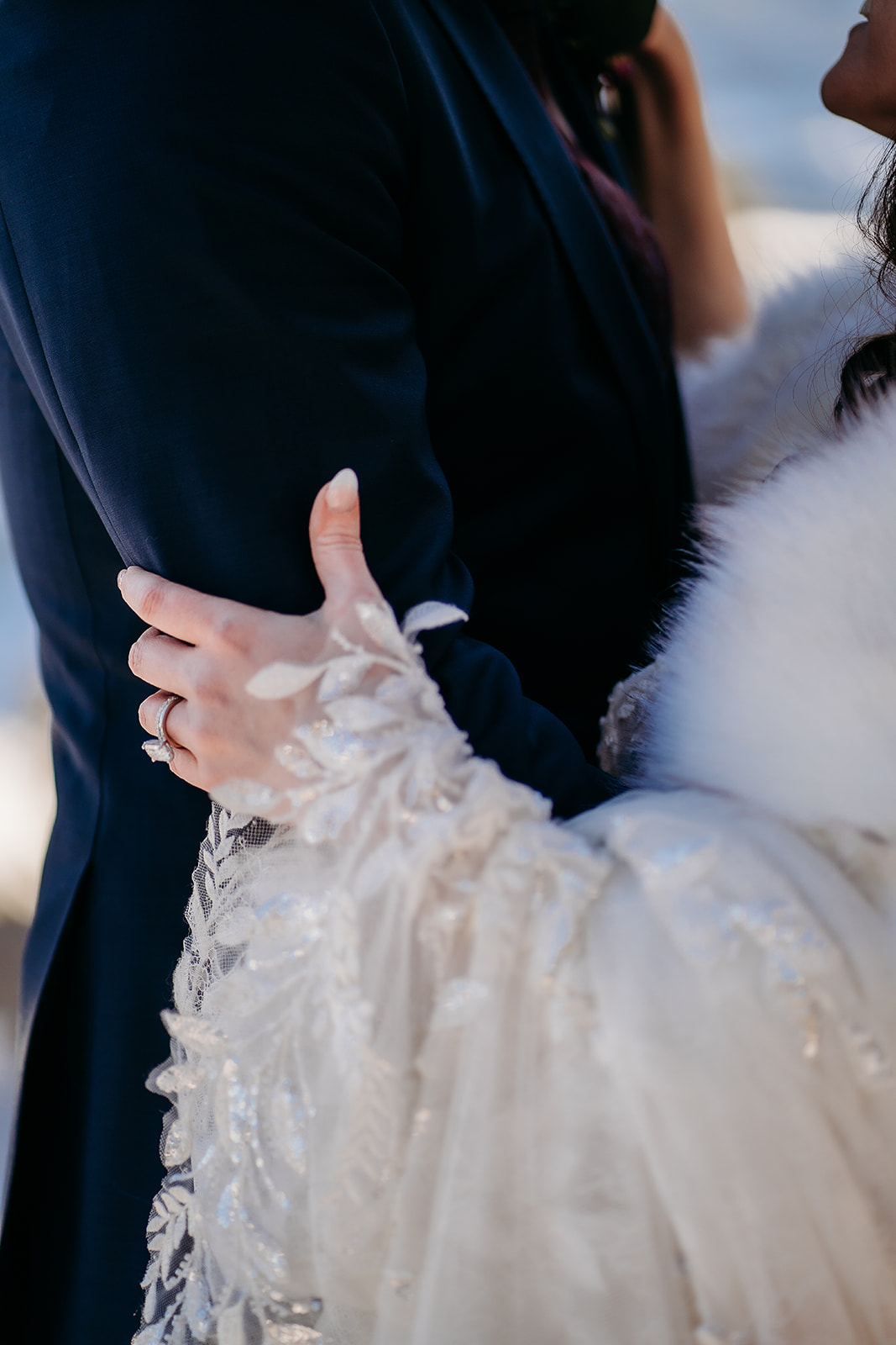 Close-up of bride’s hand resting on the groom’s arm, showcasing her engagement ring and delicate embroidered sleeve—Colorado elopement photographer.