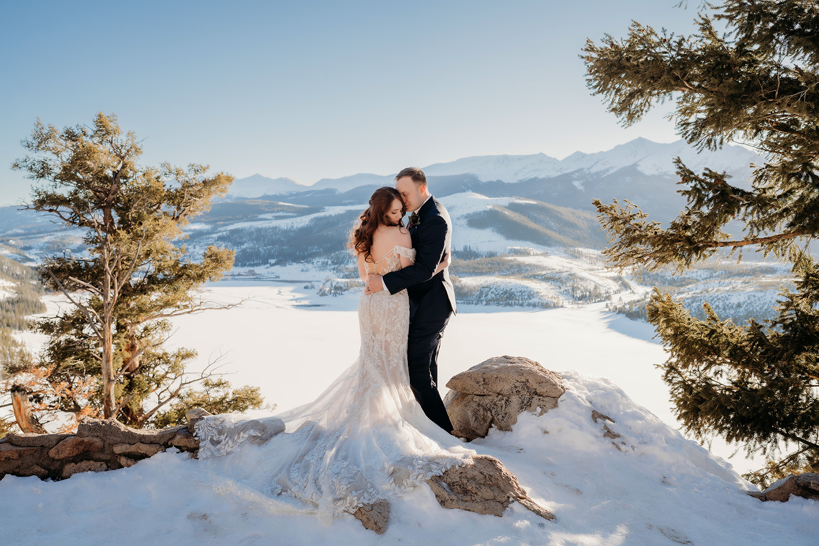 Bride and groom embrace on a snowy overlook with sweeping Colorado mountain views, captured by a Colorado elopement photographer on the best day of your life.