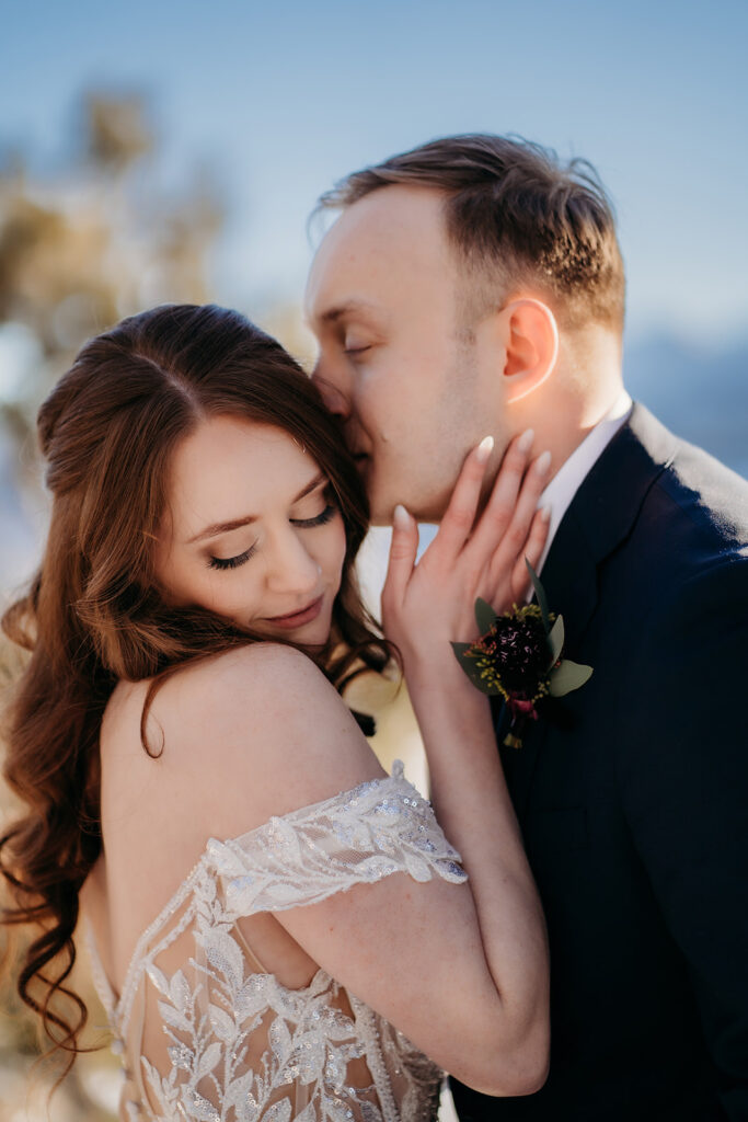 Groom gently kisses bride’s cheek as she leans in with a peaceful smile, embodying the best day of your life.