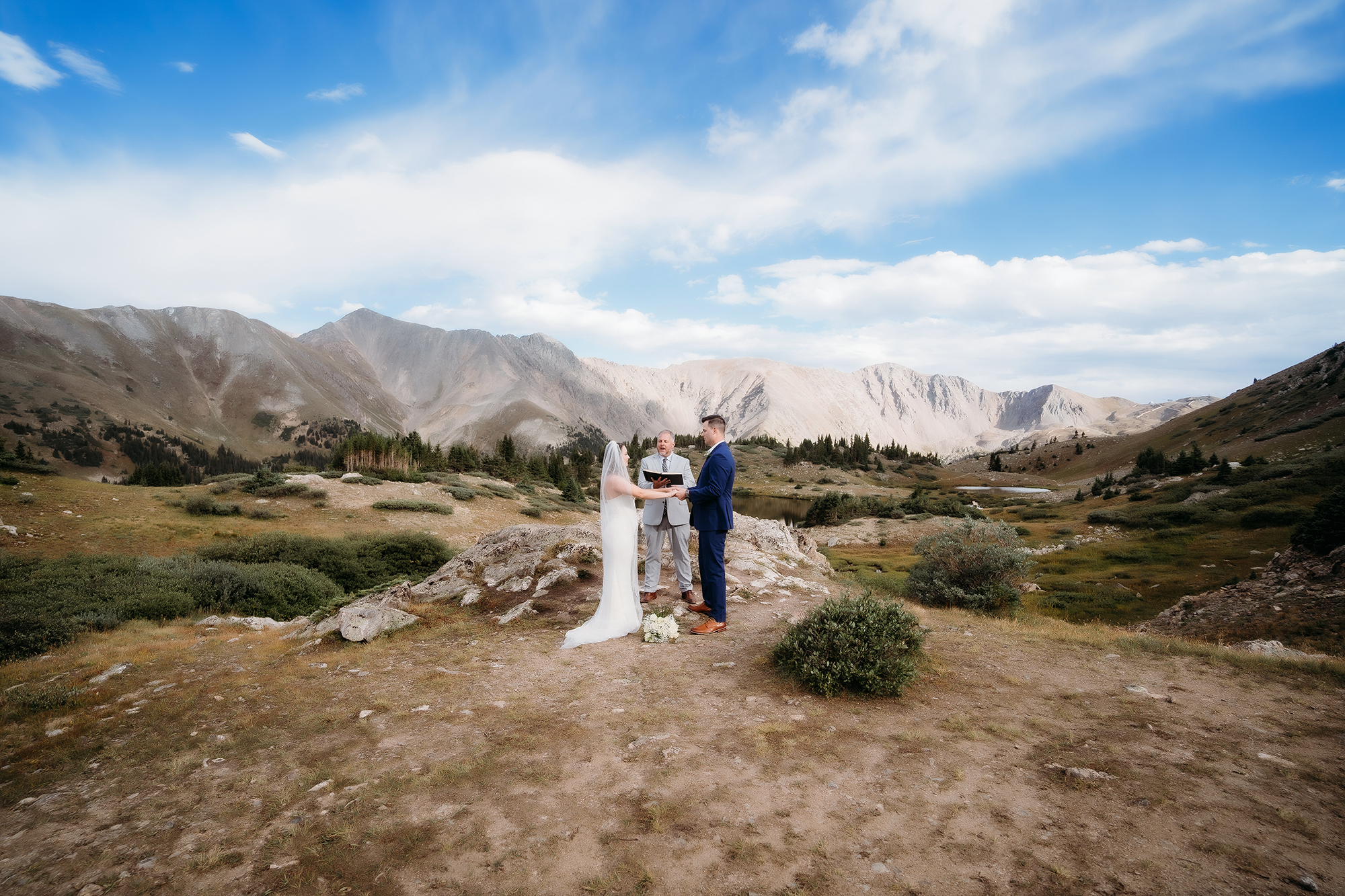 Scenic mountain elopement with a couple exchanging vows in front of their officiant — Colorado Elopement Checklist.