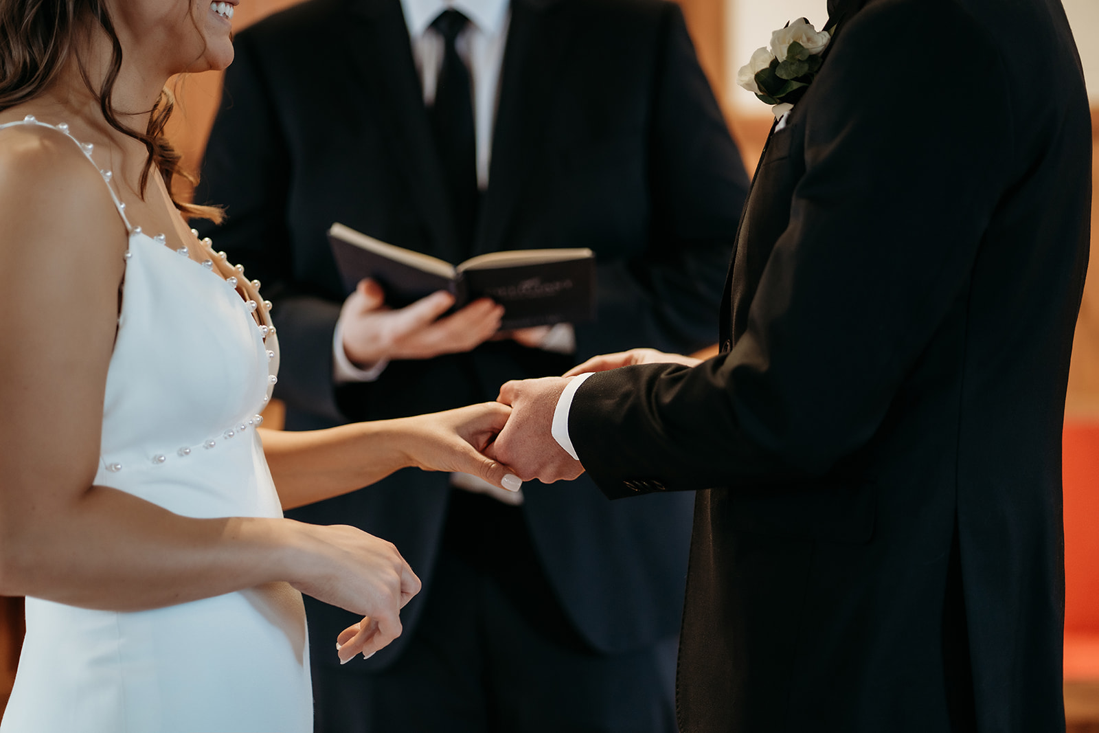 Close-up of couple exchanging rings and smiles, capturing the emotion and connection of their wedding ceremony.