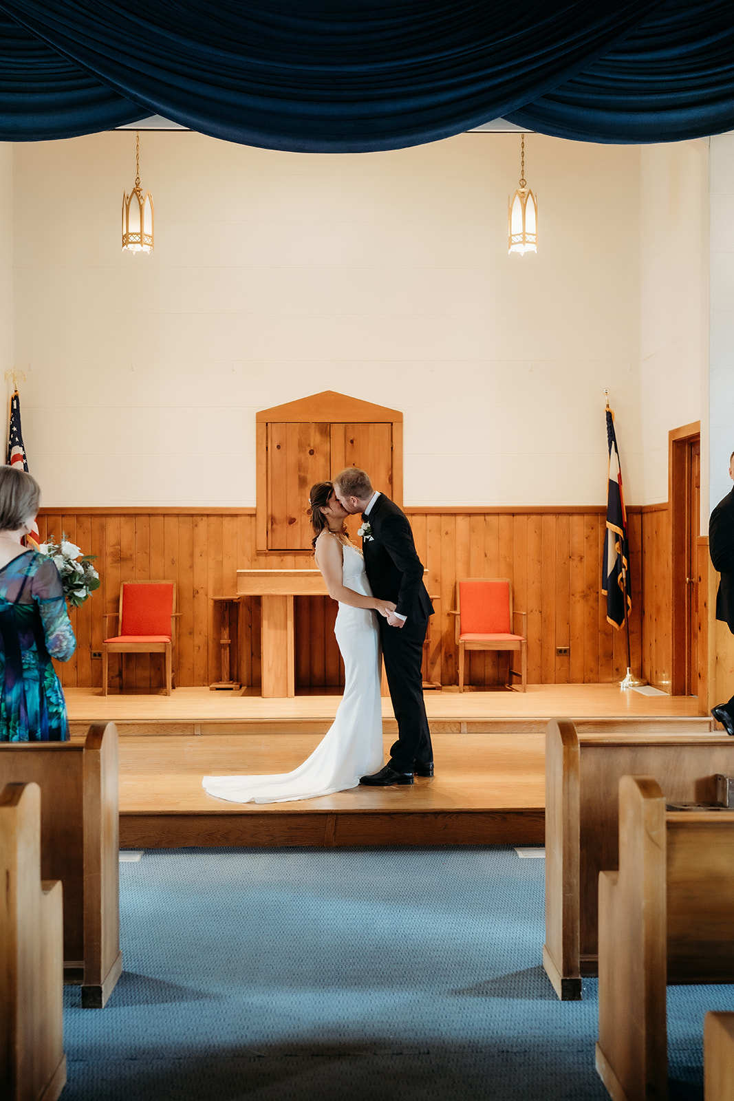 Bride and groom share their first kiss as a married couple, surrounded by loved ones during their small wedding in Colorado.