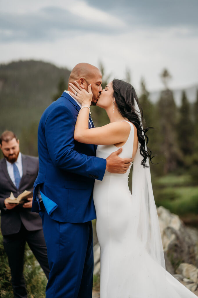 Bride and groom share a romantic first kiss after their mountain elopement ceremony.