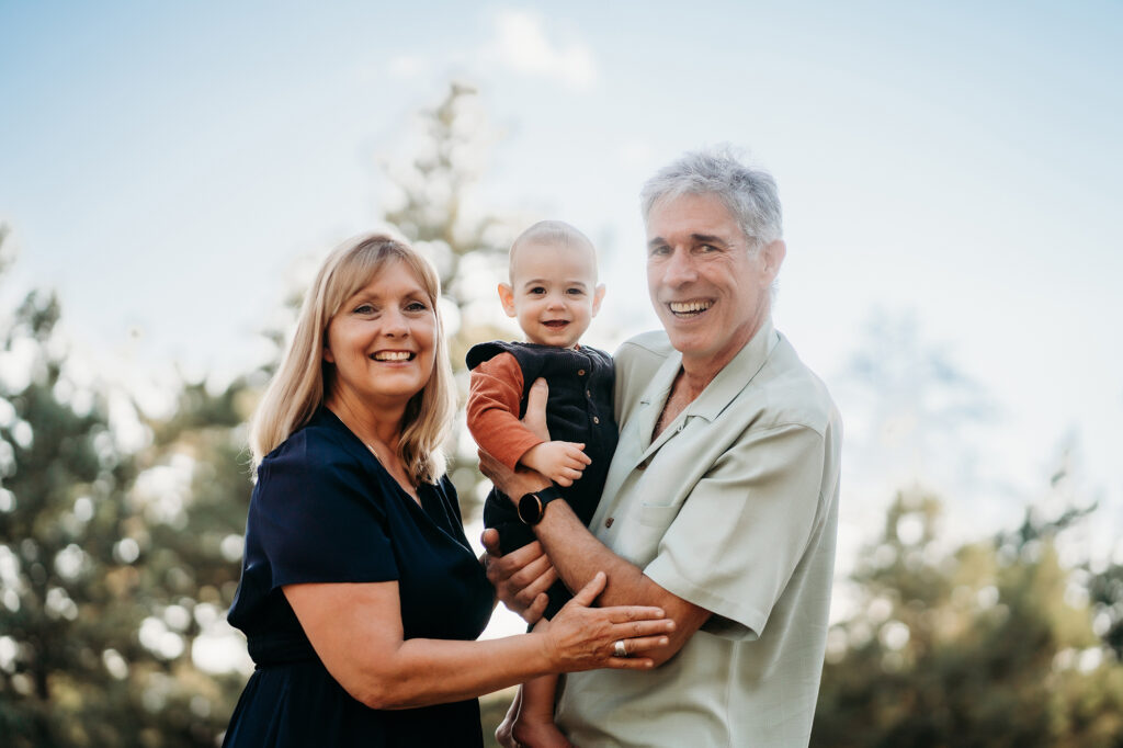 Grandparents holding grandchild during outdoor family photos