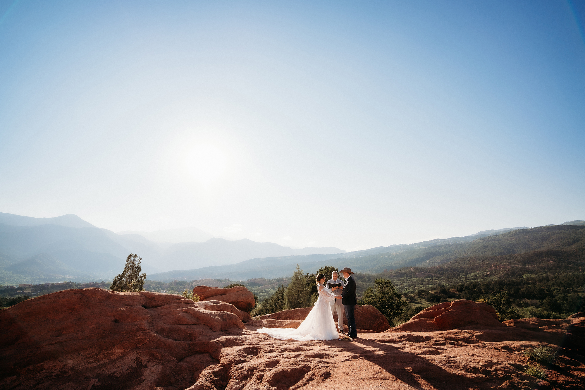 Bride and groom exchanging vows outdoors with stunning red rock formations and mountains in the background during their Denver elopement.