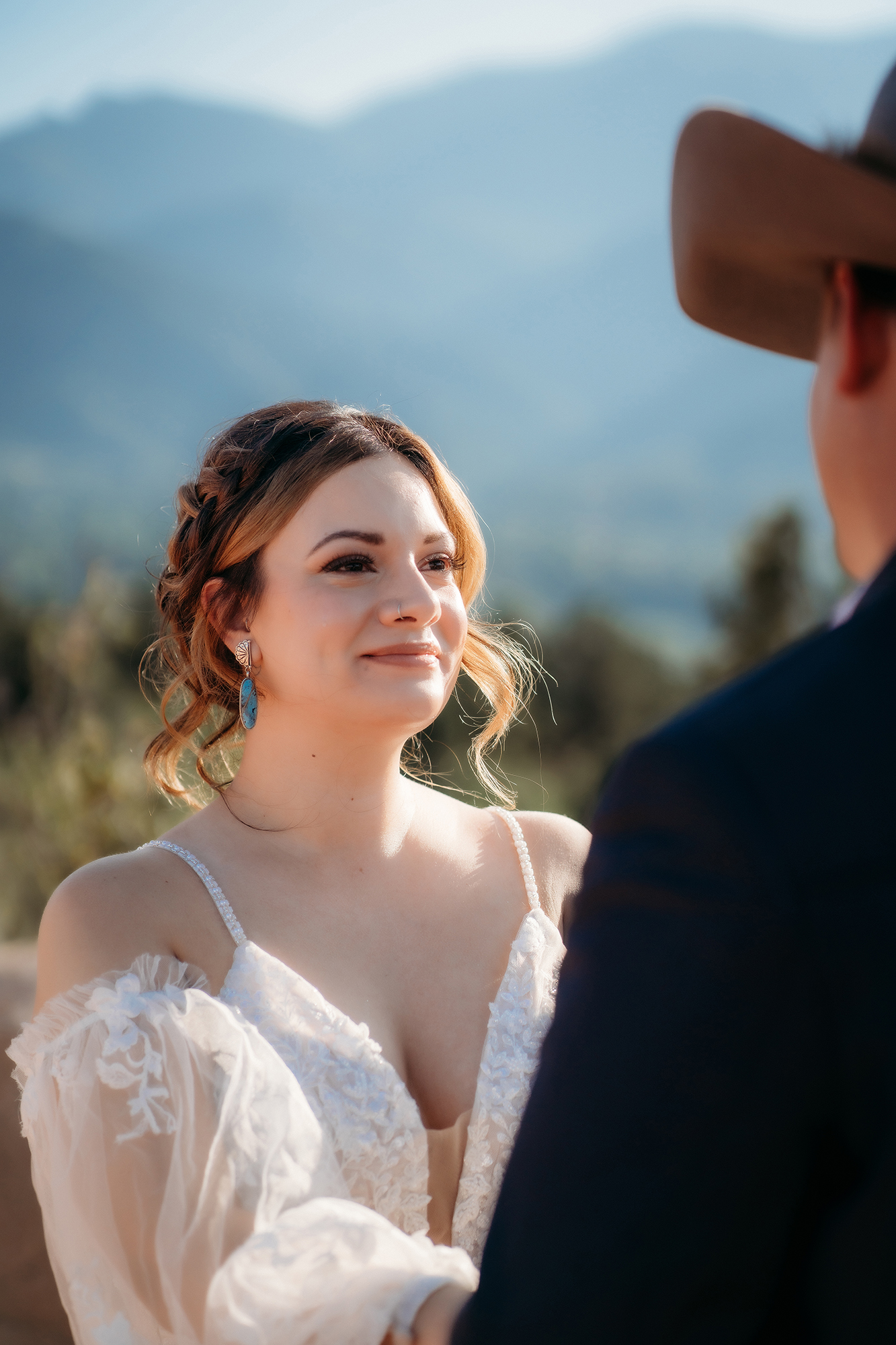 Bride smiling warmly as she listens to vows during a Denver elopement ceremony, surrounded by natural rocky landscape.