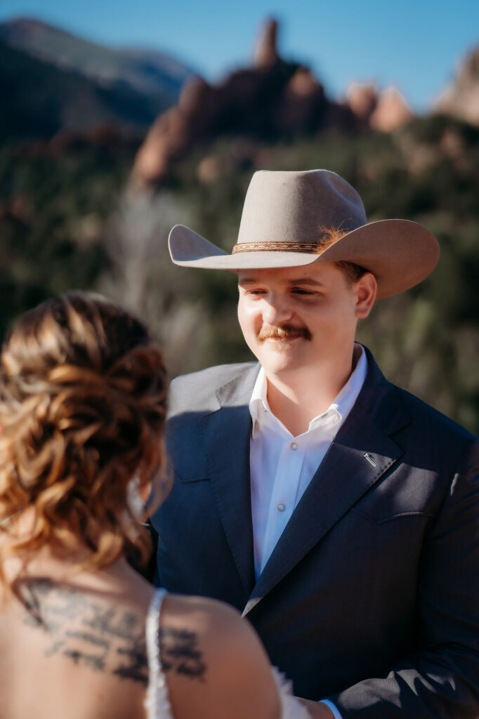 Close-up of groom in cowboy hat looking lovingly at bride during an intimate Denver elopement ceremony outdoors.