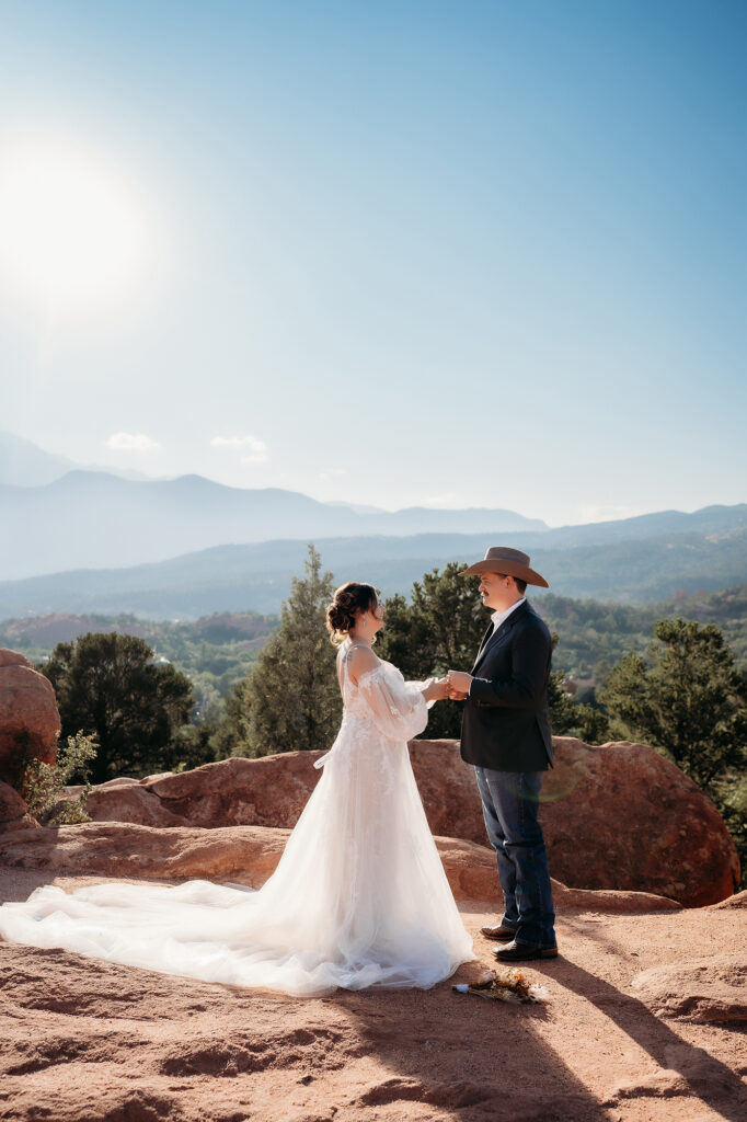 Bride and groom exchanging vows during a sunny Denver elopement ceremony surrounded by red rocks and nature.