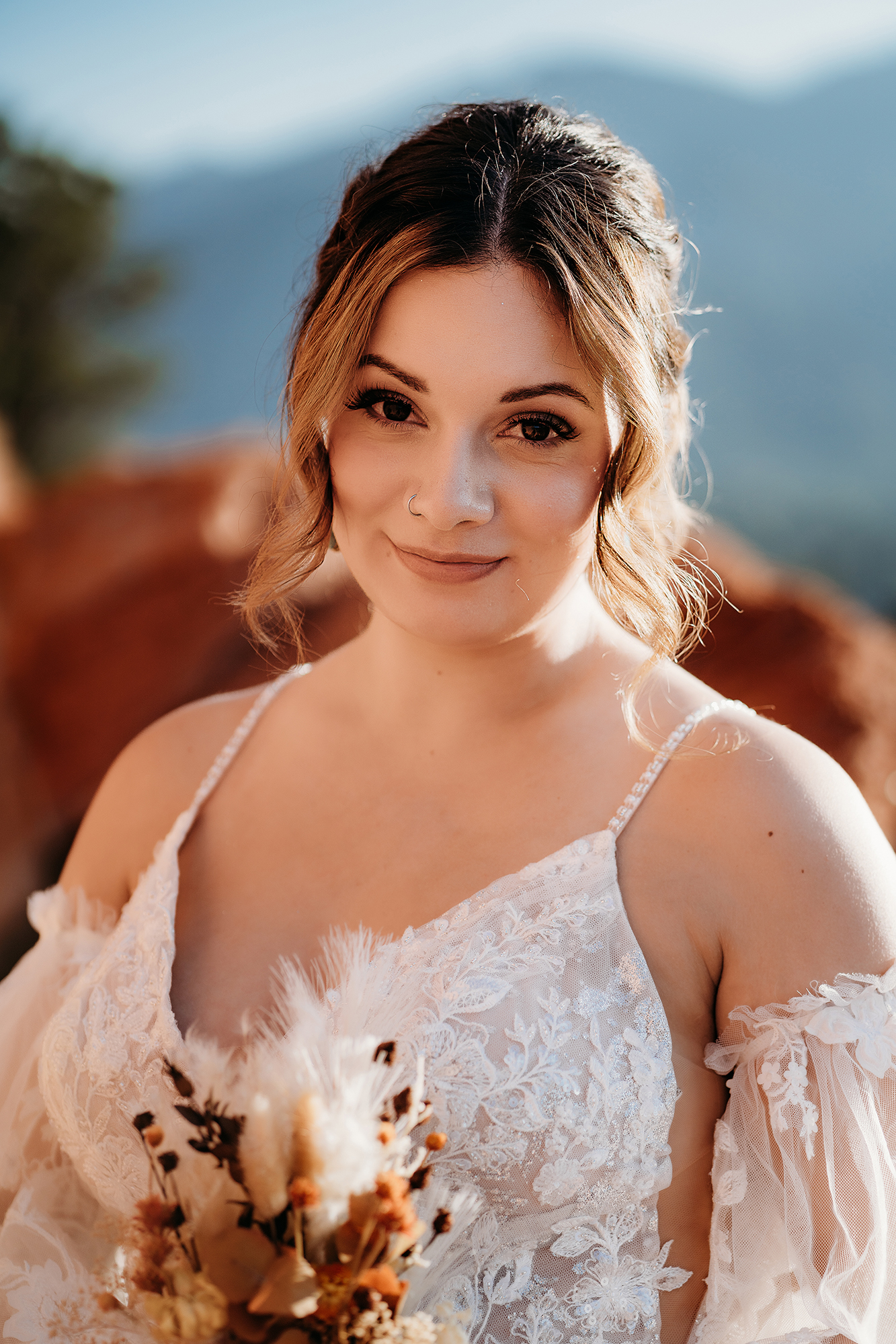 Close-up portrait of a bride in a lace gown holding a dried floral bouquet during a Denver elopement.