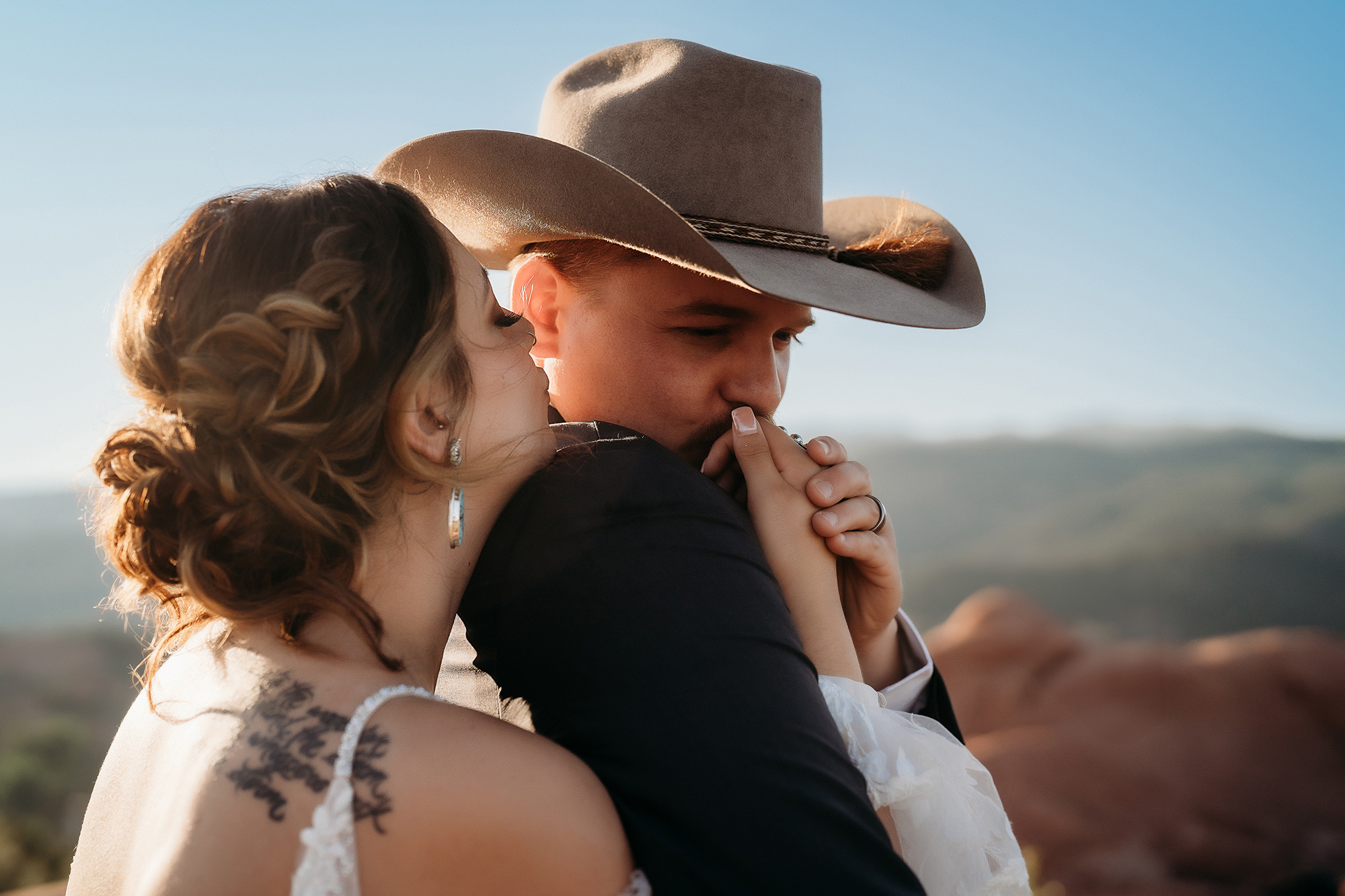 Close-up of bride kissing groom’s hand with scenic mountain views in the background during Denver elopement.