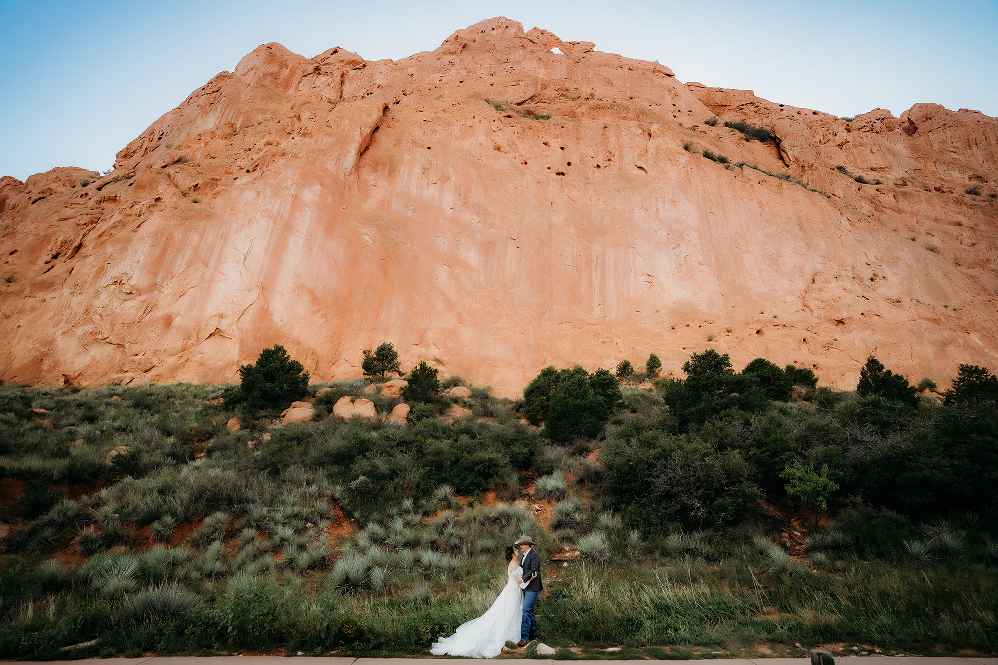 Bride and groom standing close together, sharing a kiss in front of large red rock formations at a Denver elopement.
