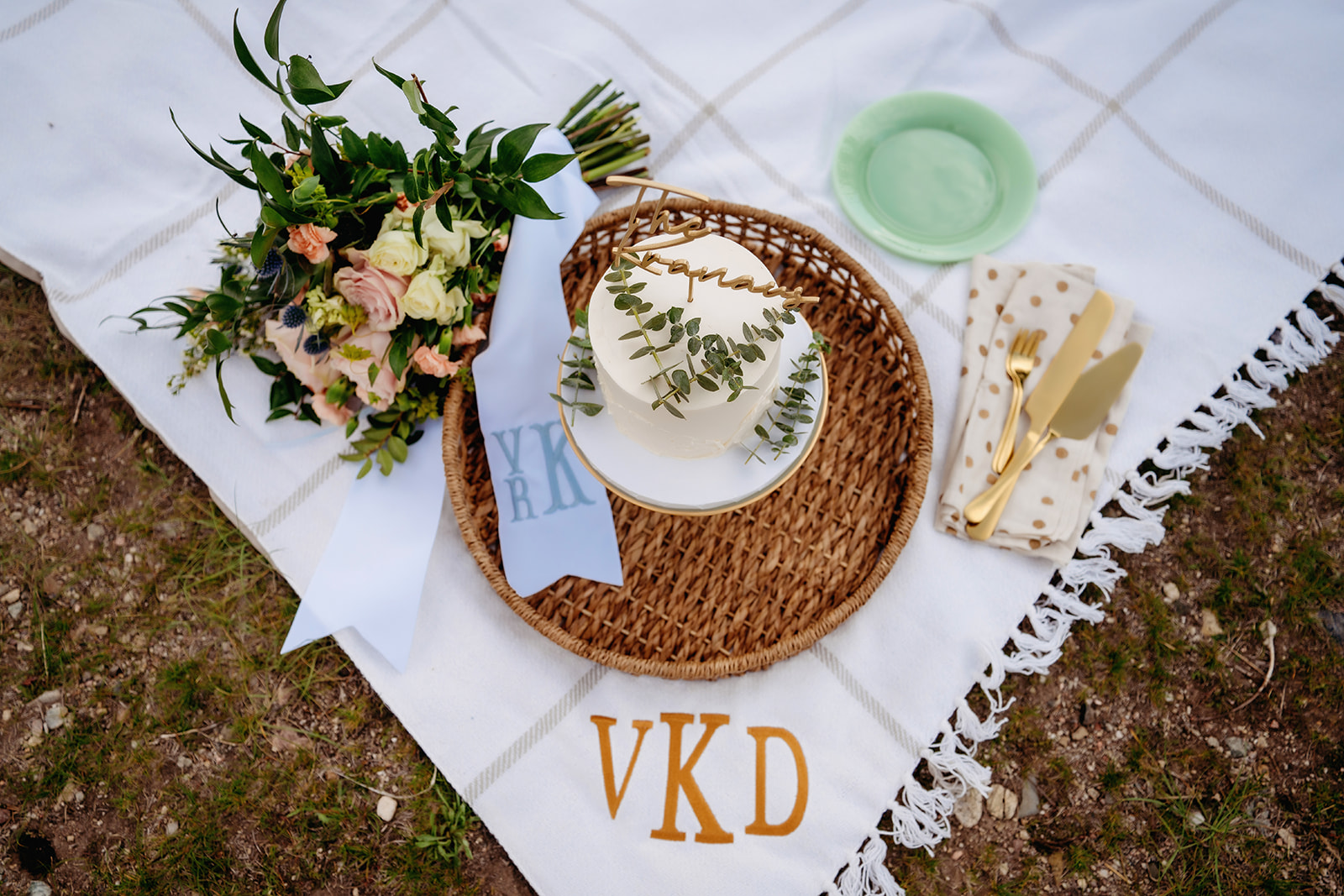 A curated picnic scene with a small cake, bouquet, and gold cutlery—a stylish way to express How to Make Your Elopement Special.