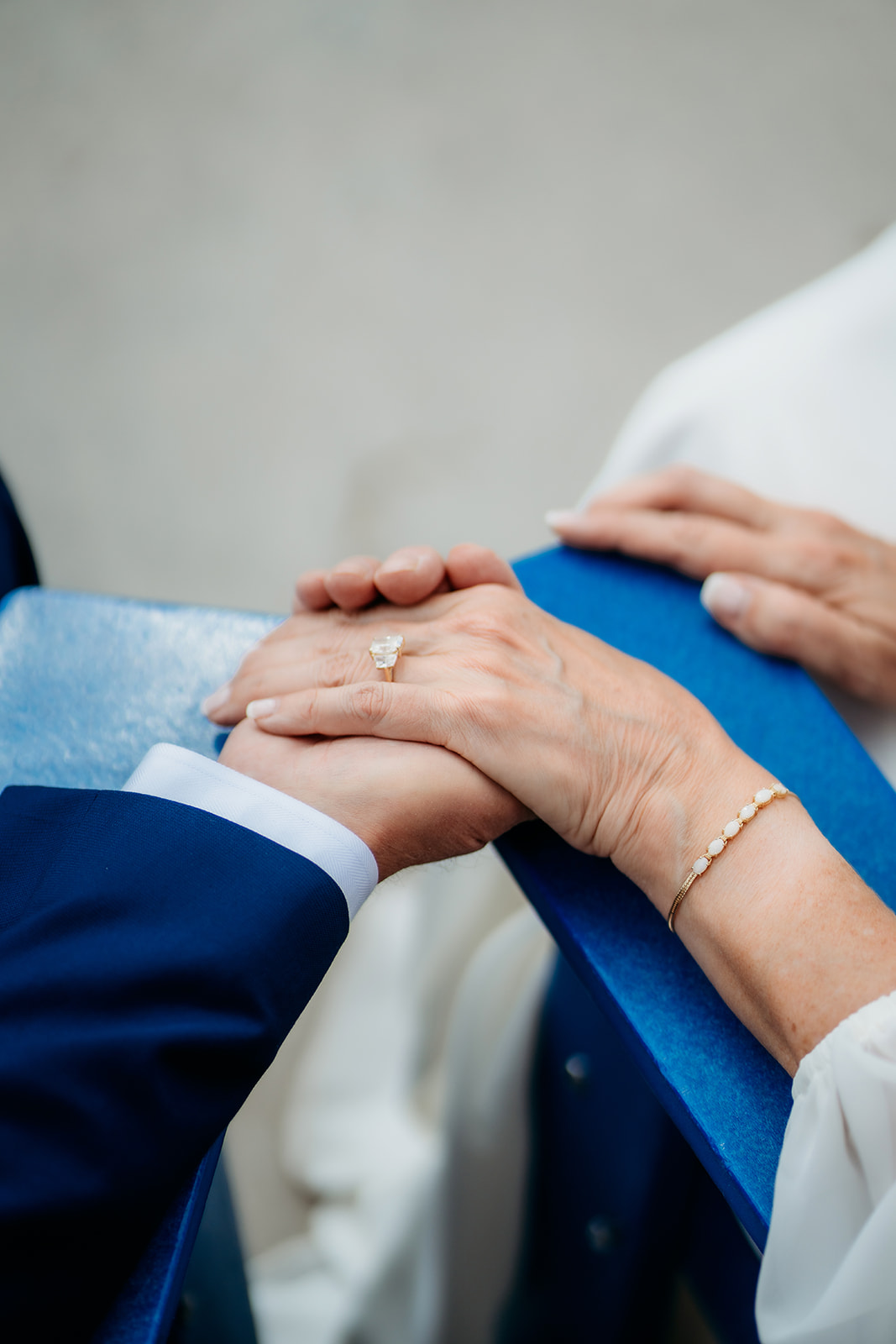 The bride’s hand rests gently over the groom’s, showcasing her ring and bracelet in a peaceful, detail-rich moment.