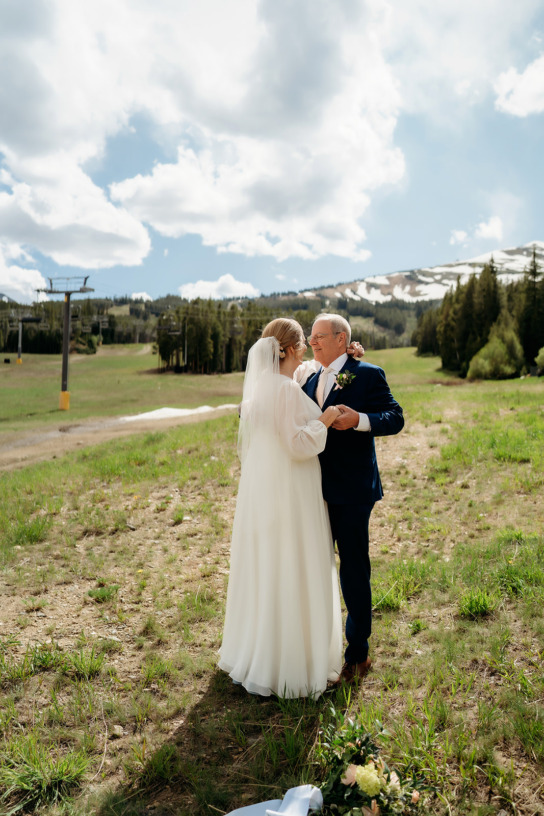 The couple shares a joyful dance in a sunlit alpine meadow with snowy peaks in the distance—an uplifting reminder of How to Make Your Elopement Special by choosing a location that feels like you.