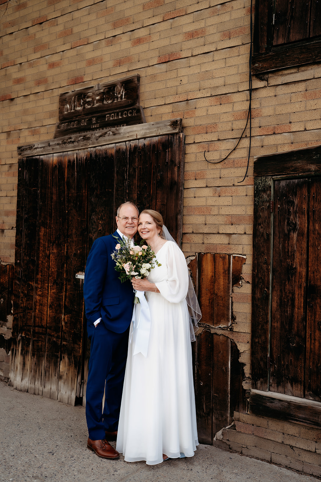 The couple shares a quiet embrace outside a weathered, historic building in downtown Breckenridge.
