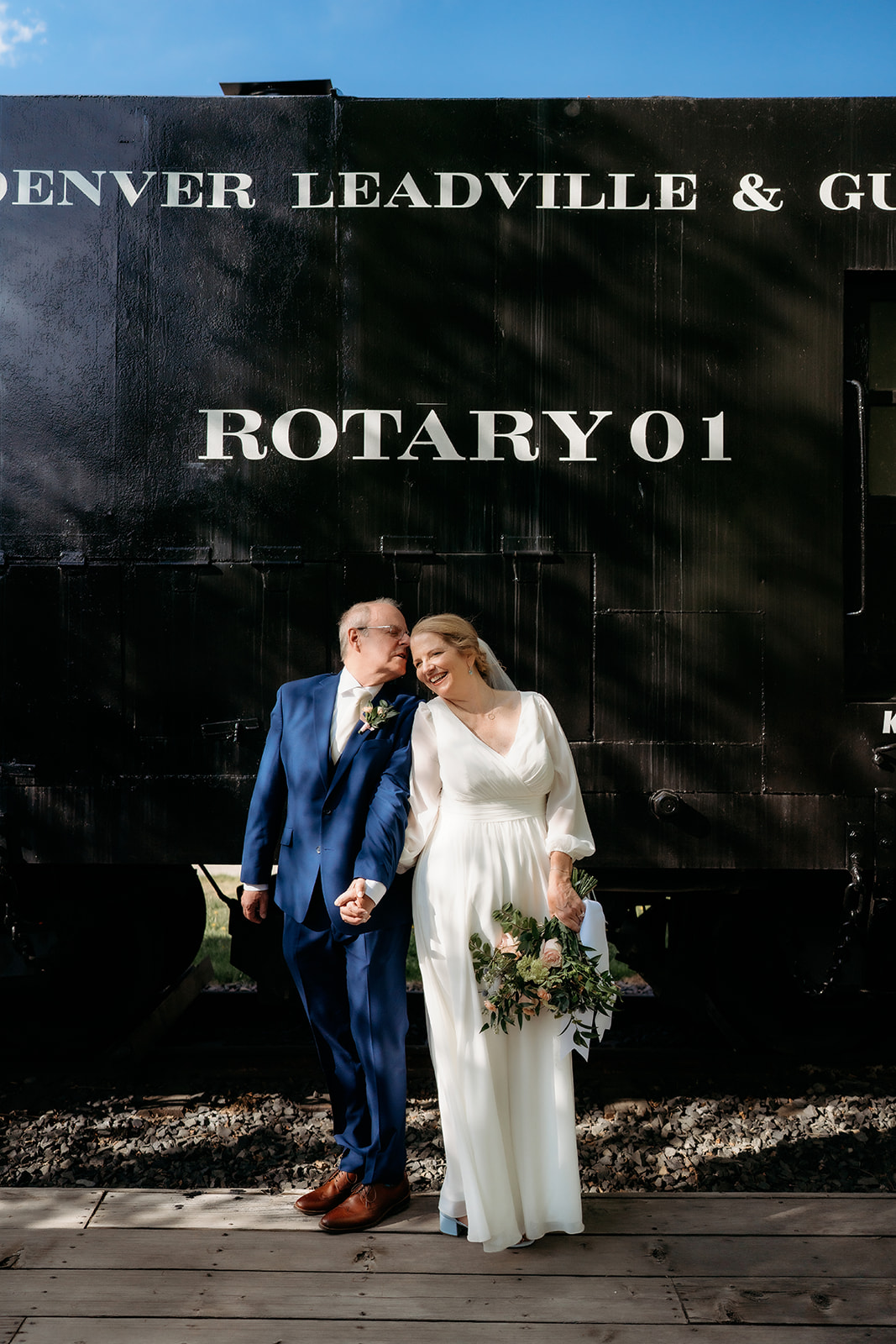 Standing in front of a black Rotary 01 train car, the couple adds vintage charm to their portraits—an idea for How to Make Your Elopement Special.