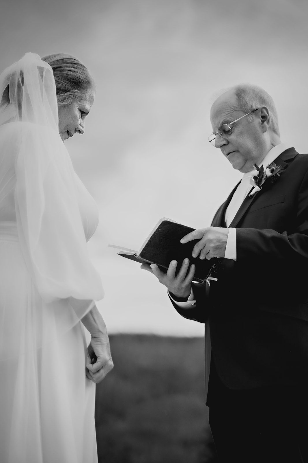 A timeless black and white shot of the groom reading his vows aloud as the bride listens, eyes full of emotion.