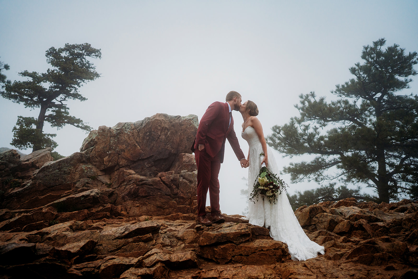 Couple shares a kiss on a rocky overlook, capturing the adventurous spirit of How to Plan an Elopement in Colorado.