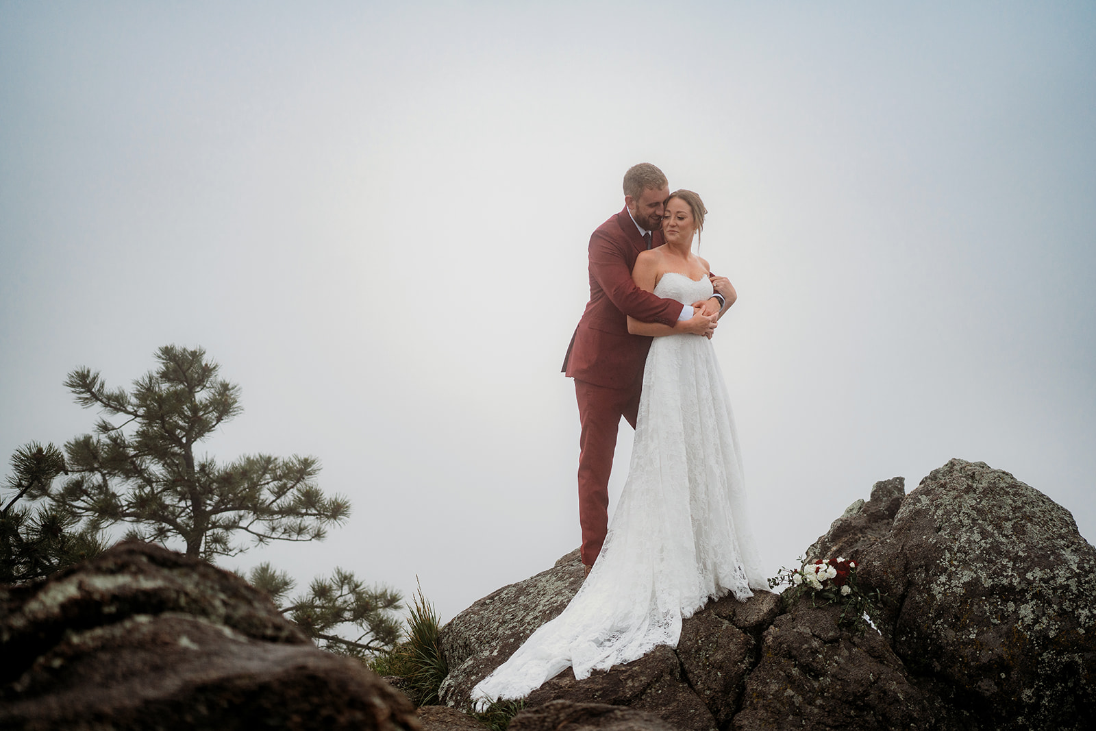 Bride and groom embracing on a mountaintop, a beautiful example of how to plan an elopement with stunning views.