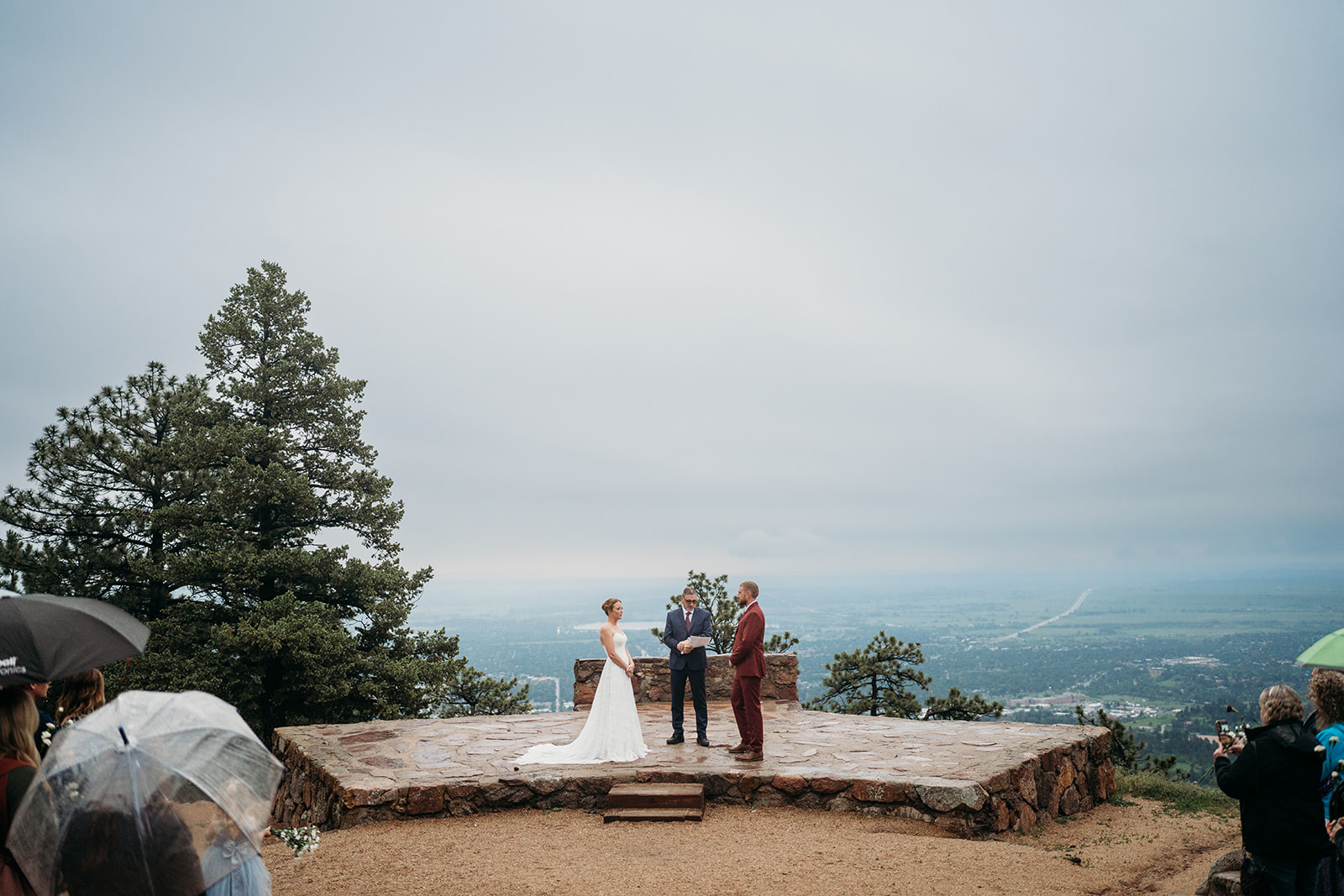 Wide view of bride and groom standing with officiant on a stone altar, a perfect example of How to Plan an Elopement outdoors.