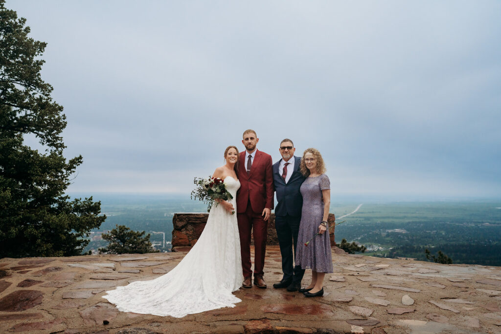 Bride and groom pose with family members on a scenic mountain overlook.