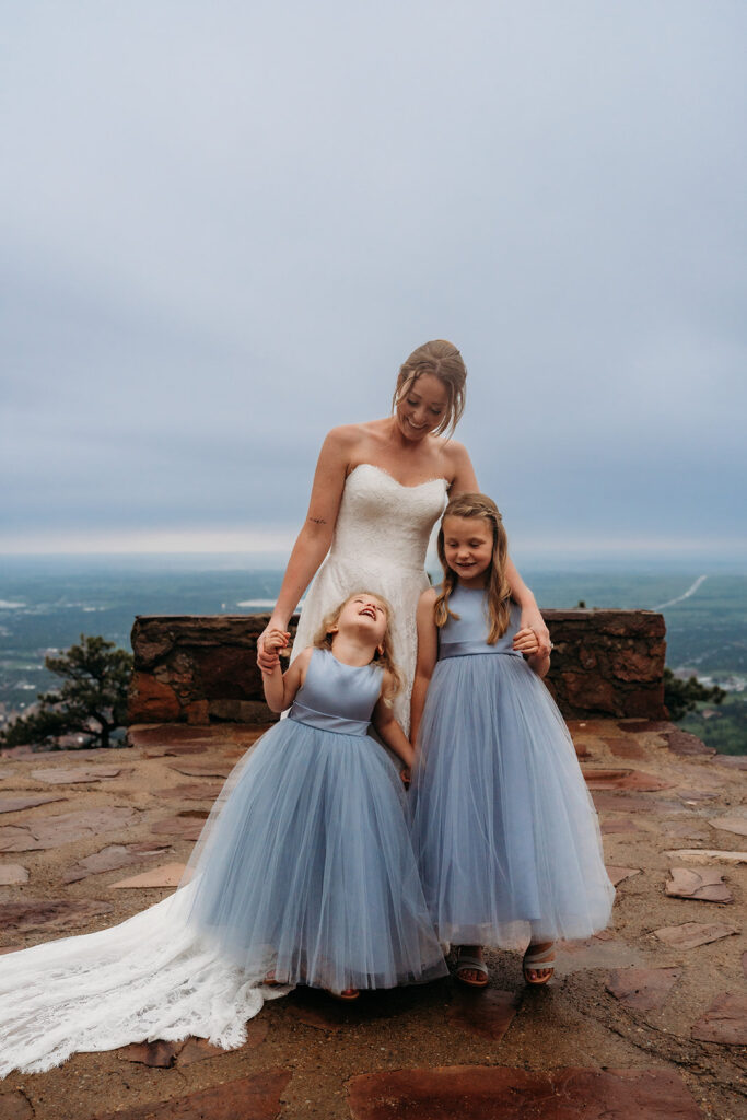 Bride smiles with two flower girls in matching blue dresses during the ceremony.