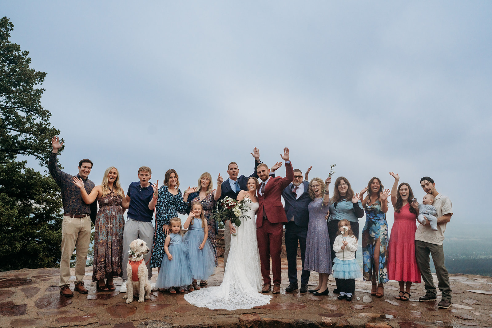 Large group photo of the wedding party and family celebrating together outdoors.