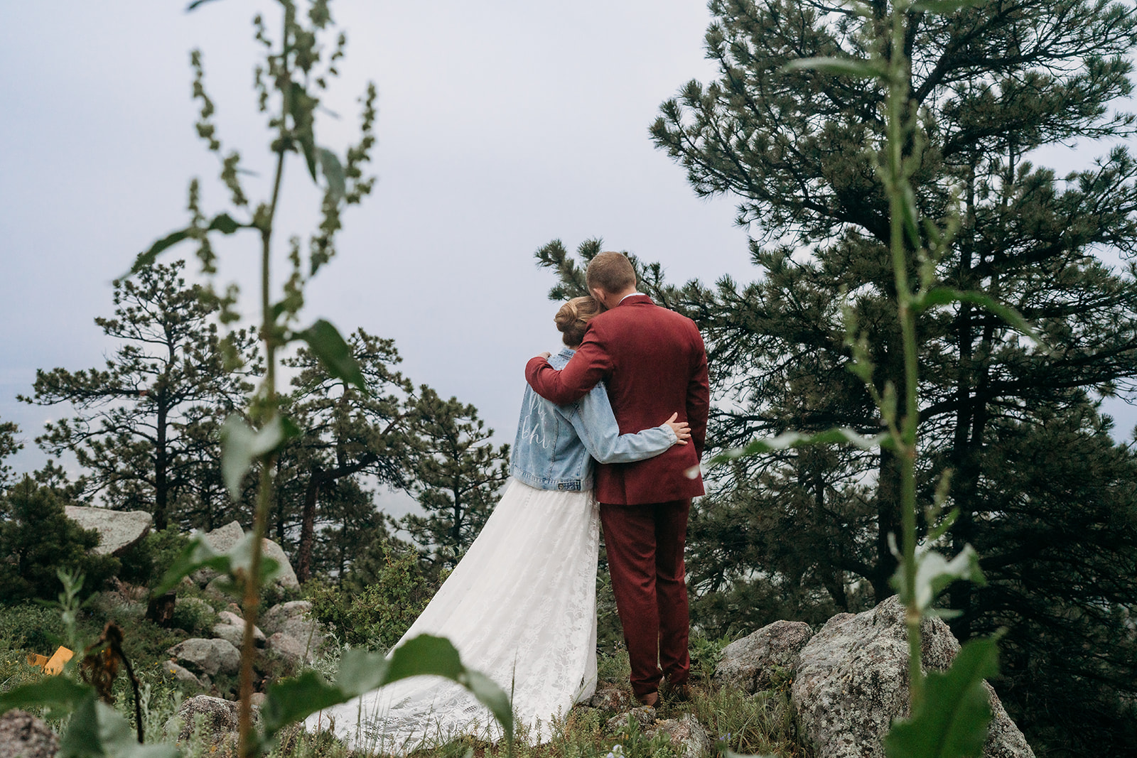 Bride and groom embrace while overlooking the forested mountains, a romantic example of How to Plan an Elopement with scenic views.