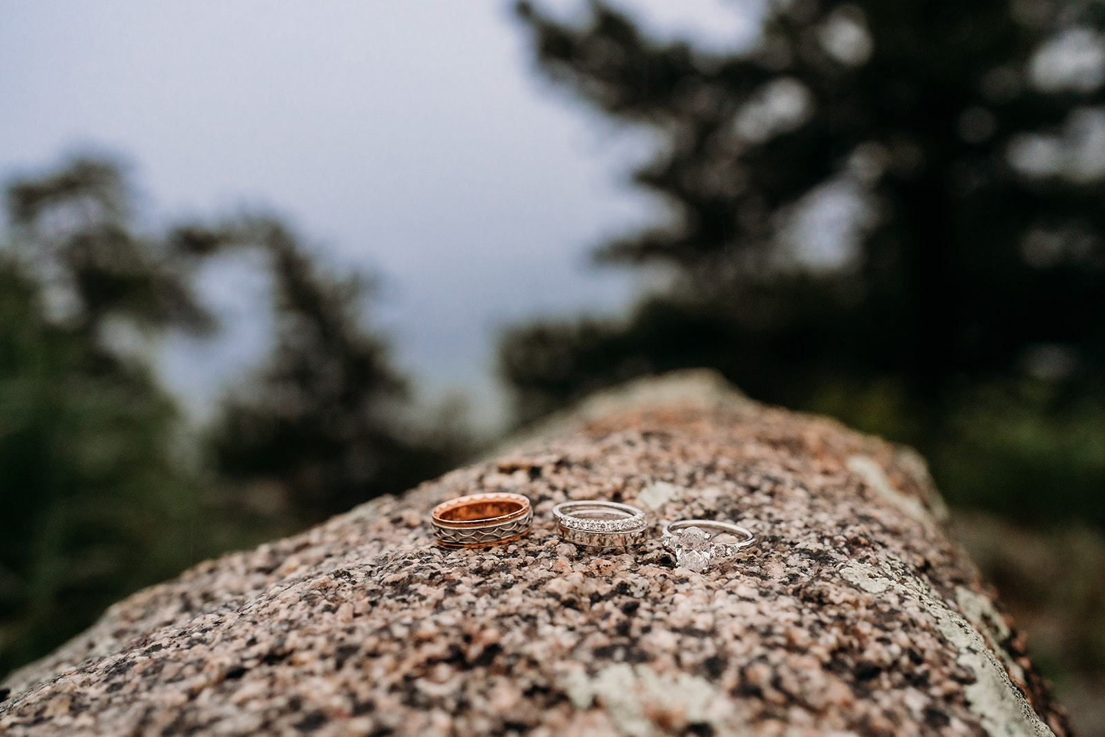 Three wedding bands placed together on a rocky surface, captured as part of elopement details.