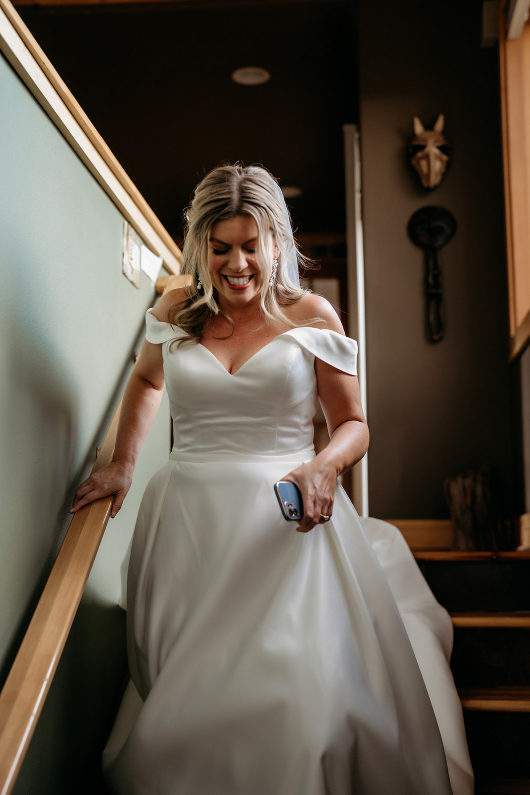 Bride in an off-the-shoulder gown smiling as she walks down the stairs to her Colorado adventure elopement.