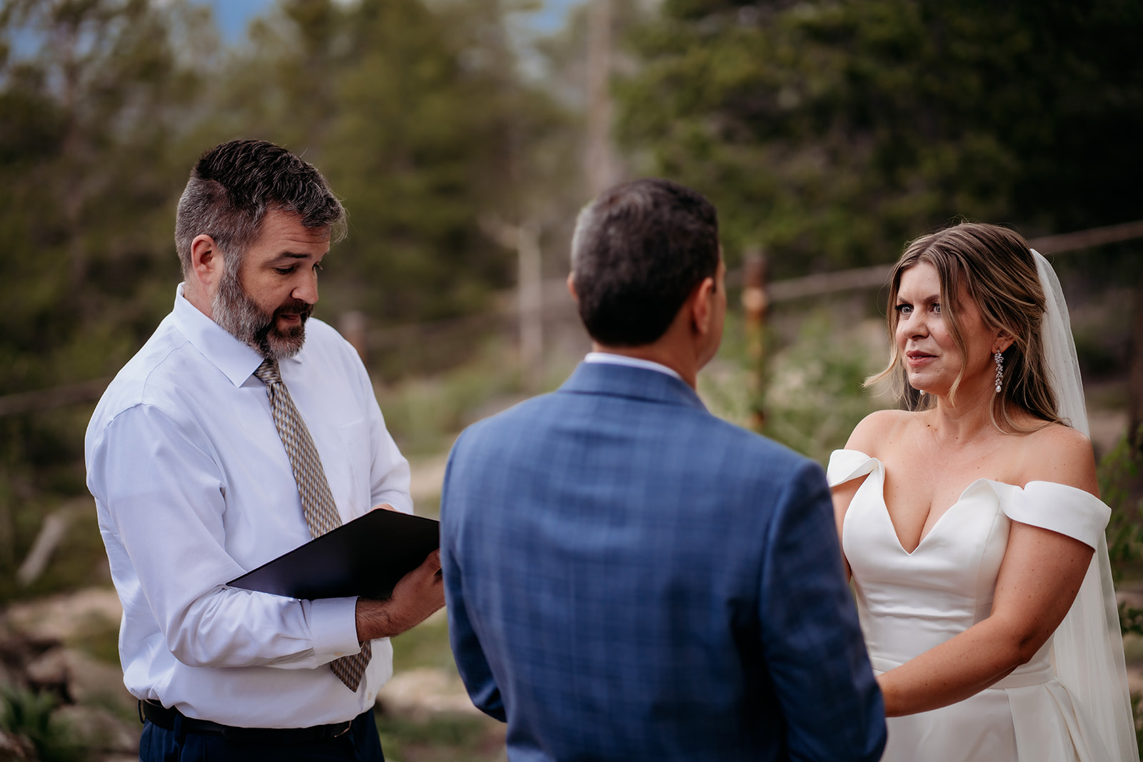 Bride and groom standing with officiant during vows at their intimate Colorado adventure elopement.