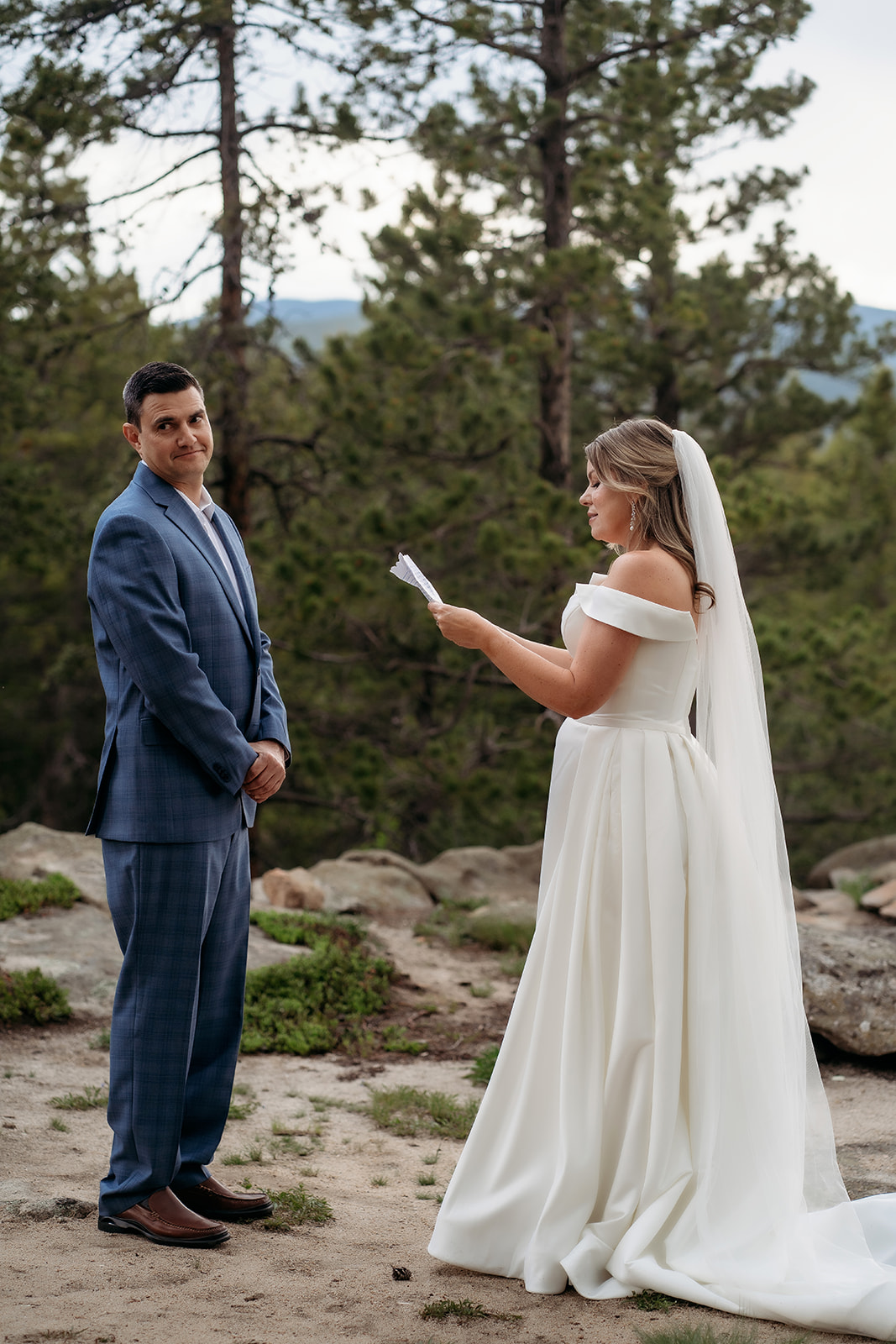 Bride reading vows to groom outdoors surrounded by pine trees at their Colorado adventure elopement.
